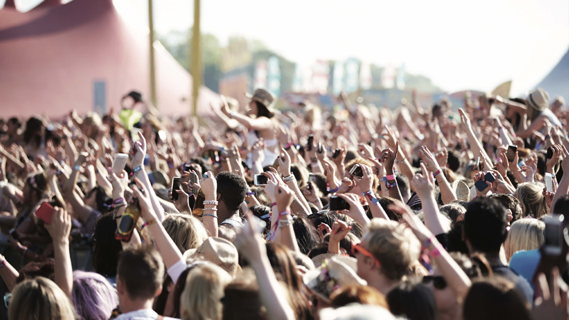 Audience at an outdoor music festival with hands in the air