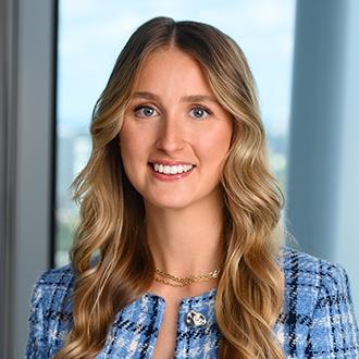 Woman with blonde wavy hair, blue jacket smiling