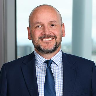 Man smiling with navy suit, checked shirt and blue tie