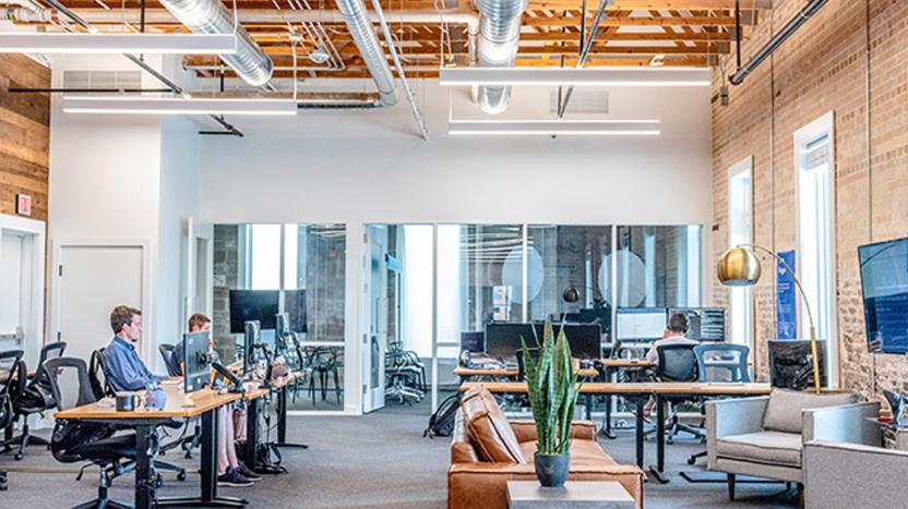 Four occupants of an otherwise empty office seated at desks, working individually on computers