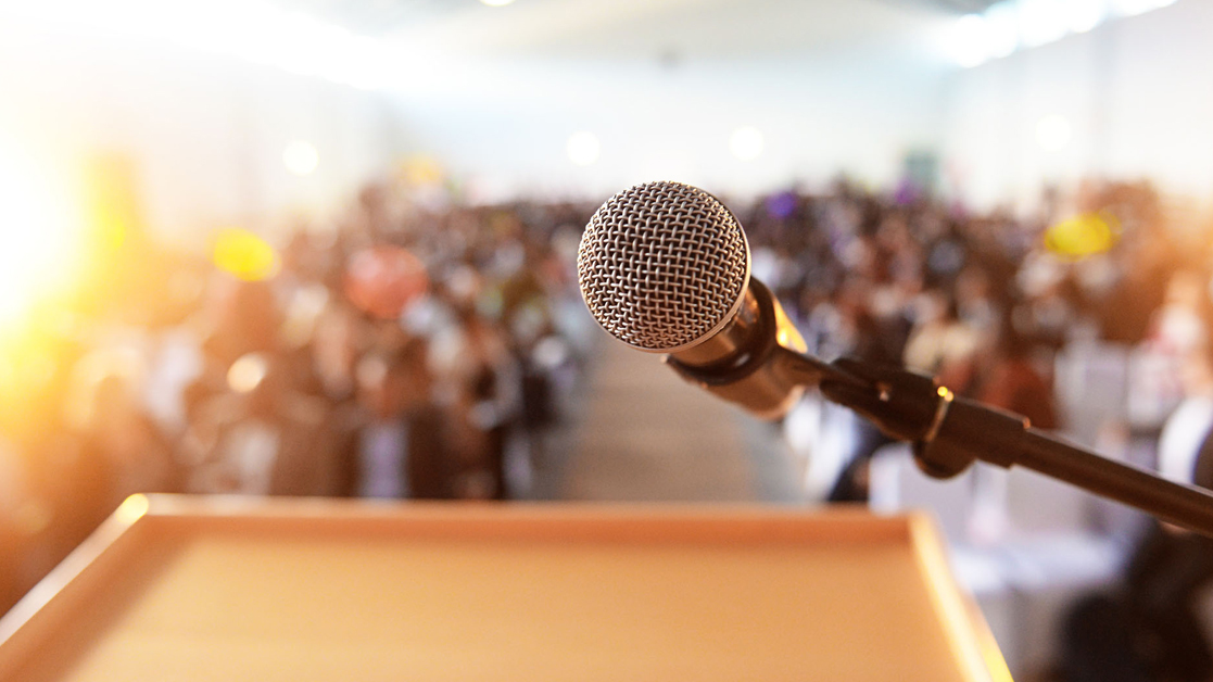 Microphone and podium with a waiting crowd in the background