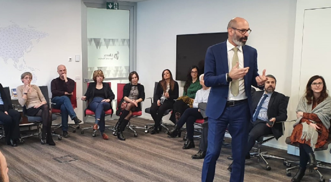 Man standing in a room talking to colleagues